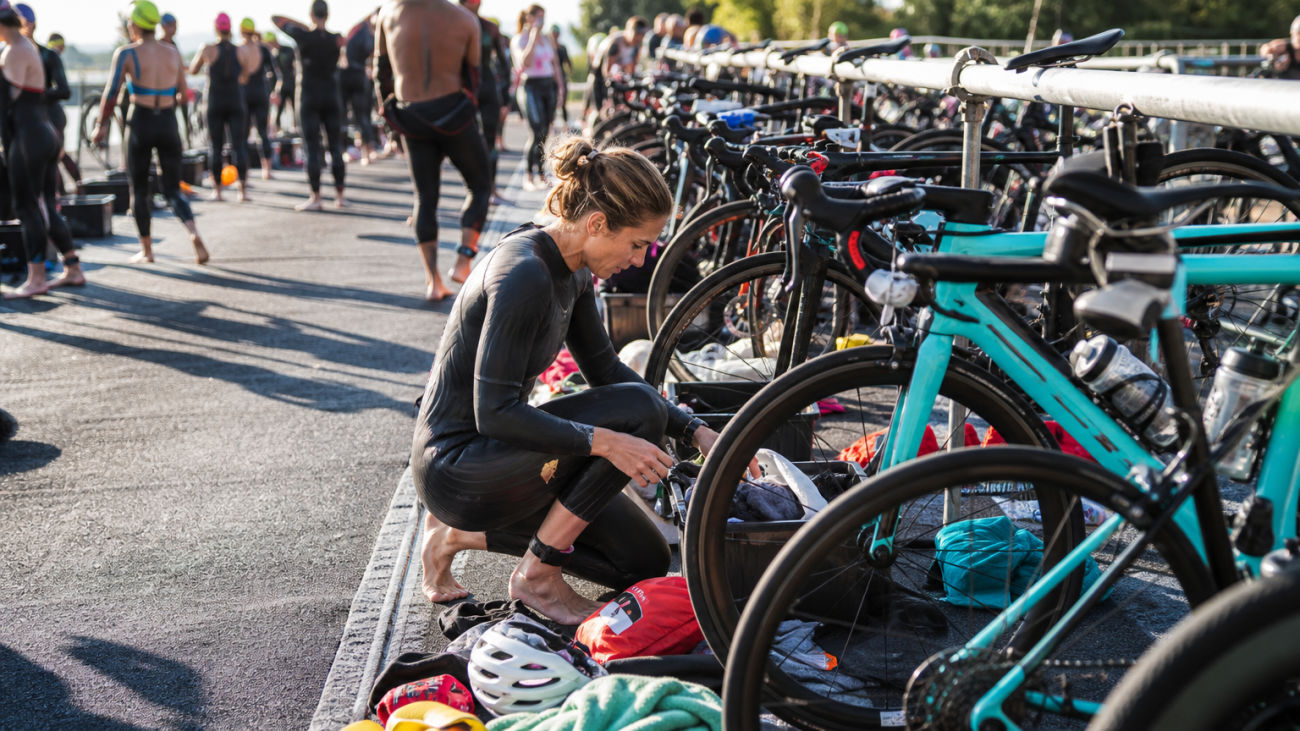 A triathlete meticulously arranges their gear in the transition area before an Ironman race.